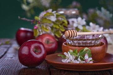 apples in a bowl with honey and apple flower on wooden table