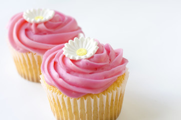 Two pink cupcakes with daisy flower decoration