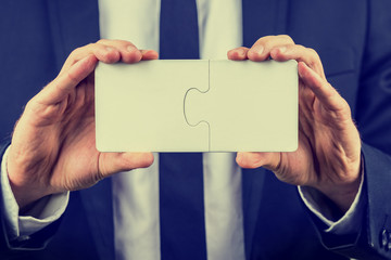 Businessman holding two interlocked puzzle pieces