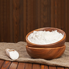 Flour in wooden bowl on nature background.