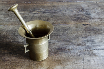 Old bronze mortar with pestle on wootden table