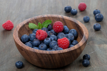 fresh blueberries and raspberries in wooden bowl