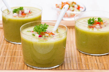green soup with fresh vegetables in glasses on wooden tray