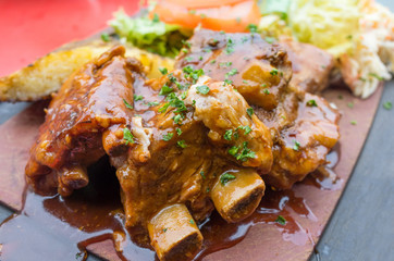 Grilled meat ribs on the plate with hot sauce