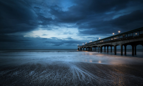 Twilight dusk landscape of pier stretching out into sea with moo - Powered by Adobe