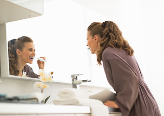 Young woman brushing teeth in bathroom