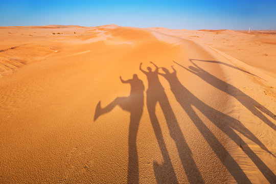 Shadow silhouettes of four people having fun in the desert 
