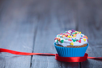 Cupcake and bow on wooden table.