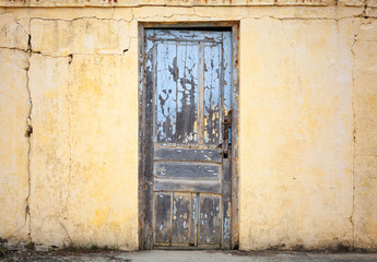 Old wooden door in yellow wall. Background photo texture