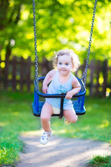 Toddler girl with curly hair wearing blue dress on playground