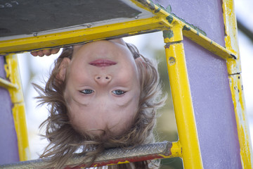 Spielplatz-Spaß: kleines Kind kopfüber auf Klettergerüst