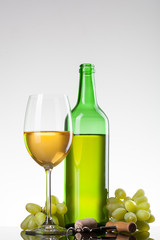 Obraz premium White wine in glass with grape and bottle