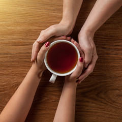 woman holding hot cup of tea with cookies