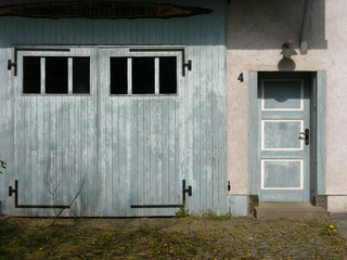 Alte Holztür und graues Garagentor eines Wohnhaus im Sonnenschein im hessischen Dorf Vetzberg im...