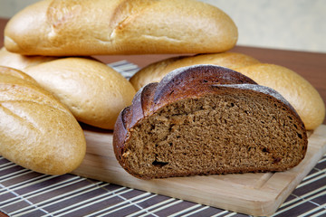 Black bread and white rolls on a kitchen table