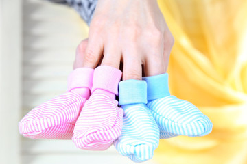 Hands with crocheted booties for baby, on light background