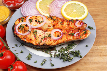 Tasty grilled salmon with vegetables, on wooden table