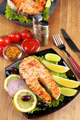 Tasty grilled salmon with lemon and vegetables, on wooden table