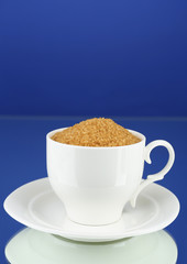 Sugar in cup on blue background