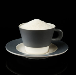 Sugar in cup isolated on black