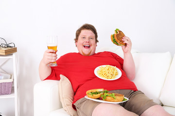 Fat man eating tasty sandwich on home interior background