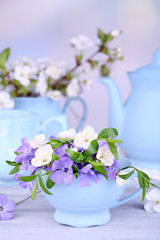 Beautiful spring flowers in cups on wooden table