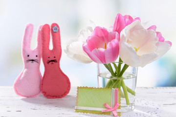Beautiful tulips in bucket in vase on table on light background