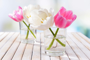 Beautiful tulips in bucket in vase on table on light background