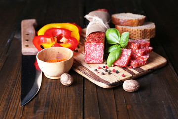 Fototapeta na wymiar Composition with knife, tasty salami sausage, sliced bread and