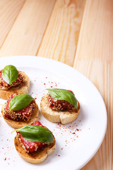Tasty canapes with salami  and basil leaves,