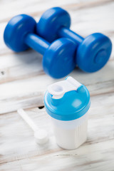 Protein shake with plastic dumbbells and a measuring scoop