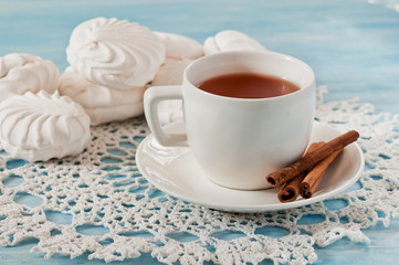 Obraz na płótnie Canvas Cup of tea with cinnamon and marshmallows on the lace napkin