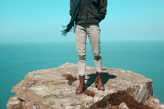 Woman standing on a cliff by the sea