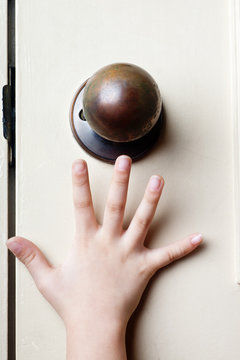 Kid's Hand Reaching Up For The Door Knob To Open It