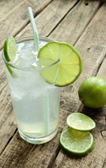 Cold and fresh drink with lime and ice on wooden table