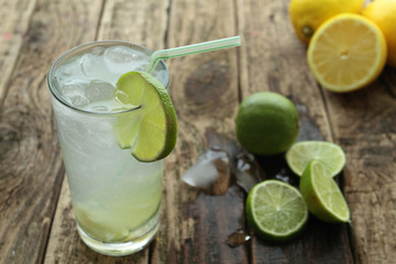 Fresh drink with lime and ice on wooden table