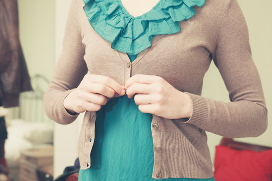 Young woman buttoning her blouse