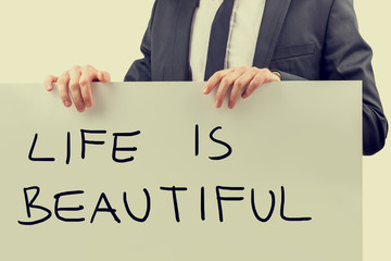 Businessman holding a Life Is Beautiful sign