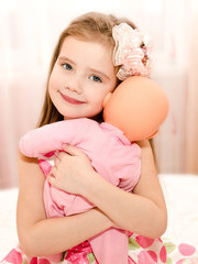 Adorable smiling little girl playing with a doll