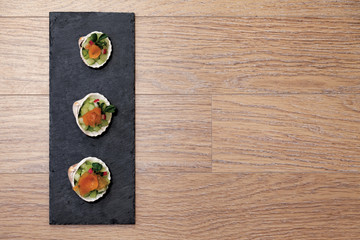 Obraz na płótnie Canvas Smoked salmon snacks served in shells, slate plate on wood