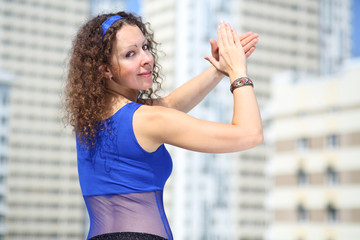 Woman in blue suit and scarf on hips looks back