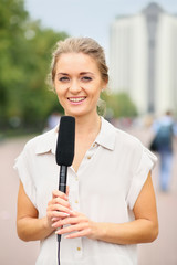 Girl reporter in white blouse and with a microphone