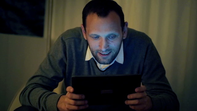 Man Playing Game On Tablet Computer In Home At Night