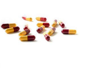 close up of yellow and red medical capsules isolated on white ba