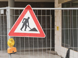 Verkehrsschild - Baustelle - älteres Modell - an einem Bauzaun