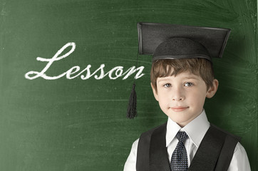 Cheerful little boy on blackboard. Looking at camera