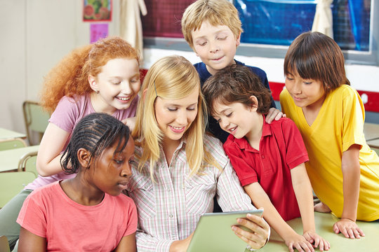 Schüler und Lehrer schauen auf Tablet PC