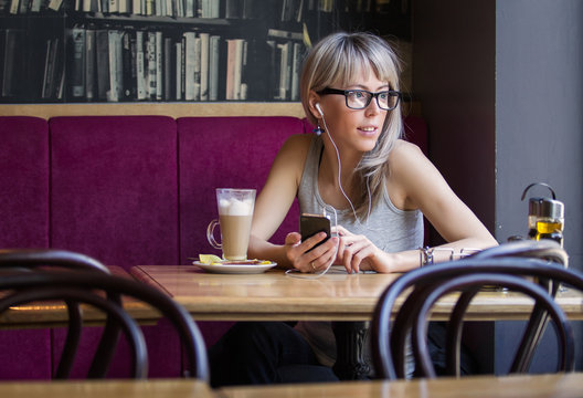 Young woman sitting in cafe and listening music