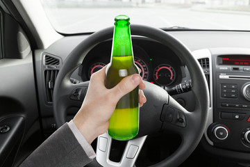 Male holding bottle of beer while driving car