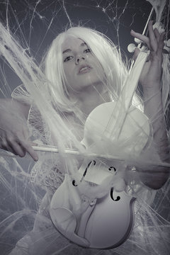 Vogue beautiful woman trapped in a spider web with a white violi